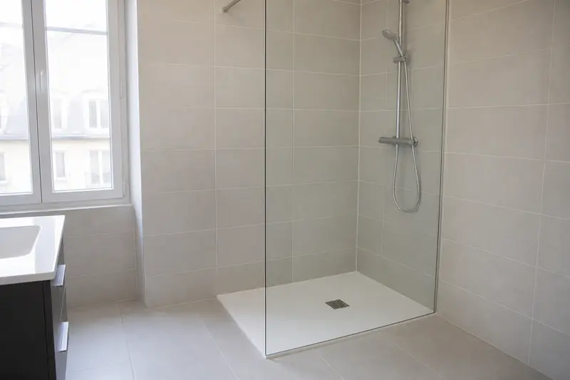Douche de plain-pied avec paroi vitrée remplaçant une baignoire dans un appartement angevin