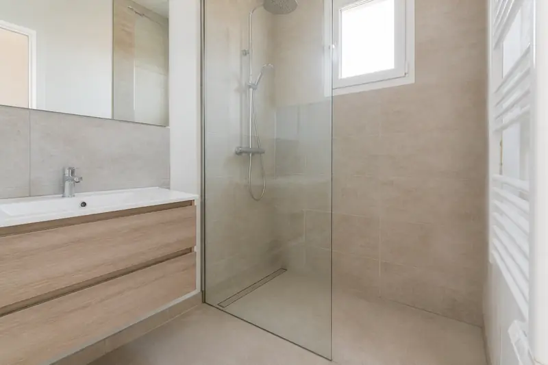 Douche à l'italienne carrelée à la place d'une baignoire d'angle dans une maison de Trélazé