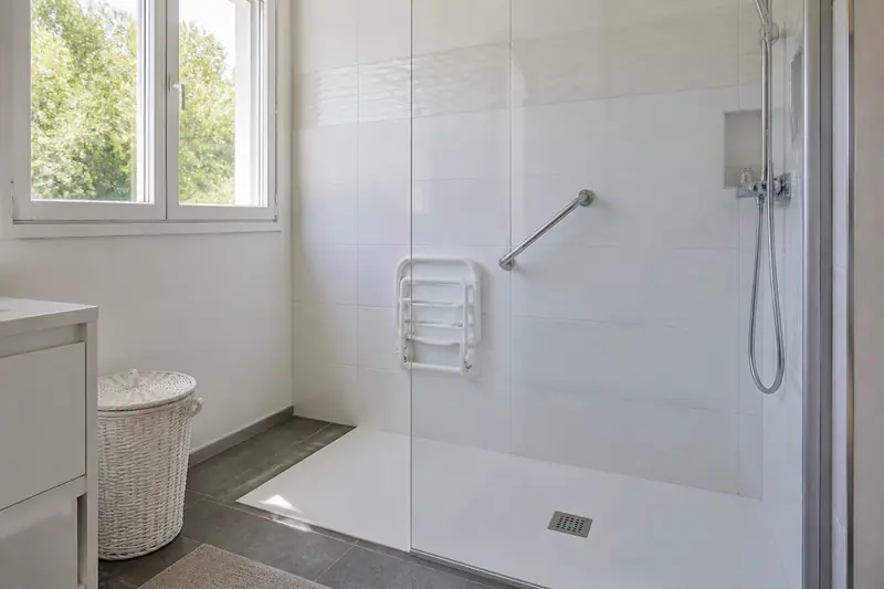 Douche de plain-pied avec barre d'appui remplaçant une baignoire dans un pavillon de Beaucouzé
